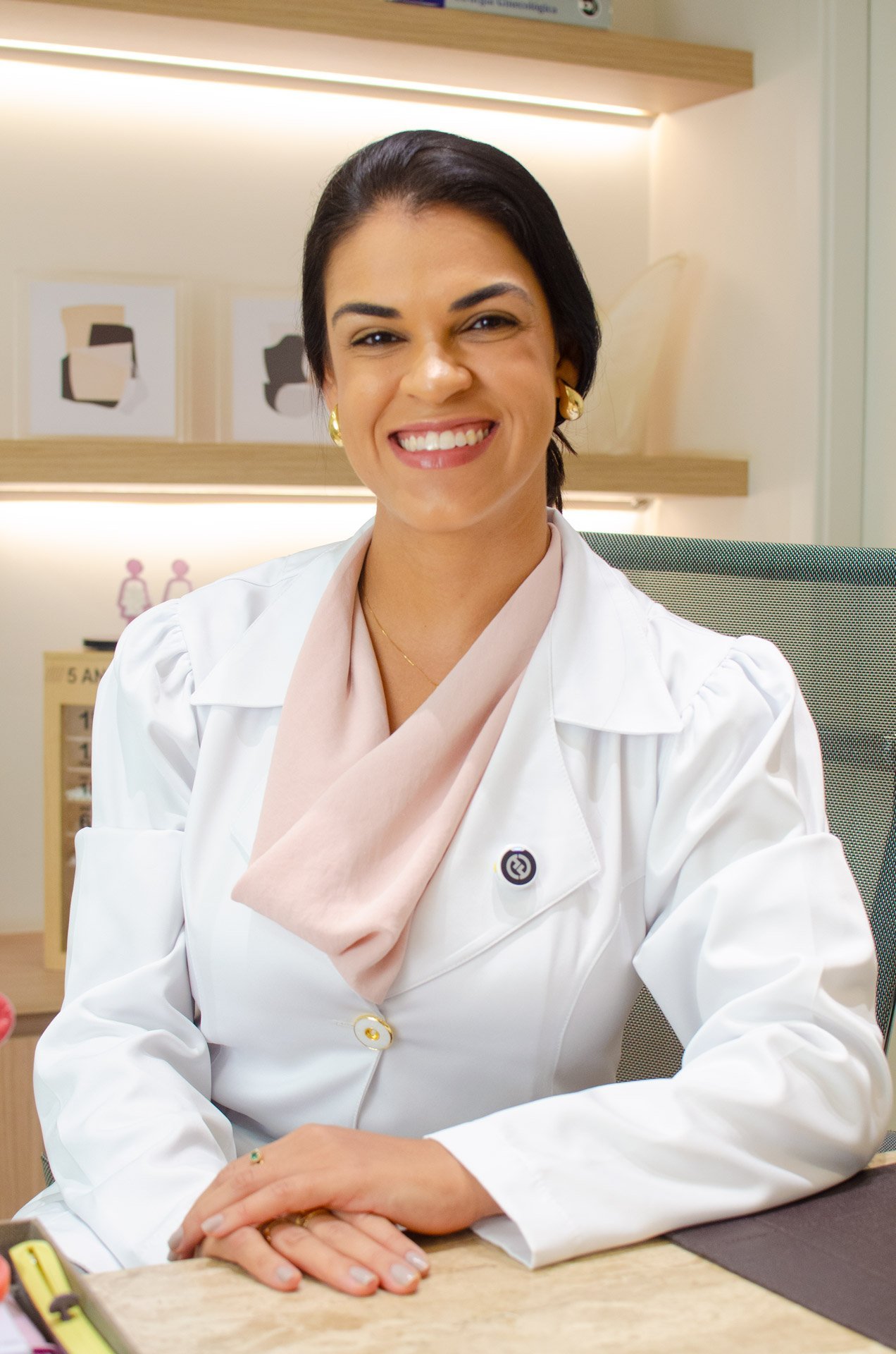 Dra. Júnea Chagas, ginecologista em Belo Horizonte, sorrindo à mesa do consultório